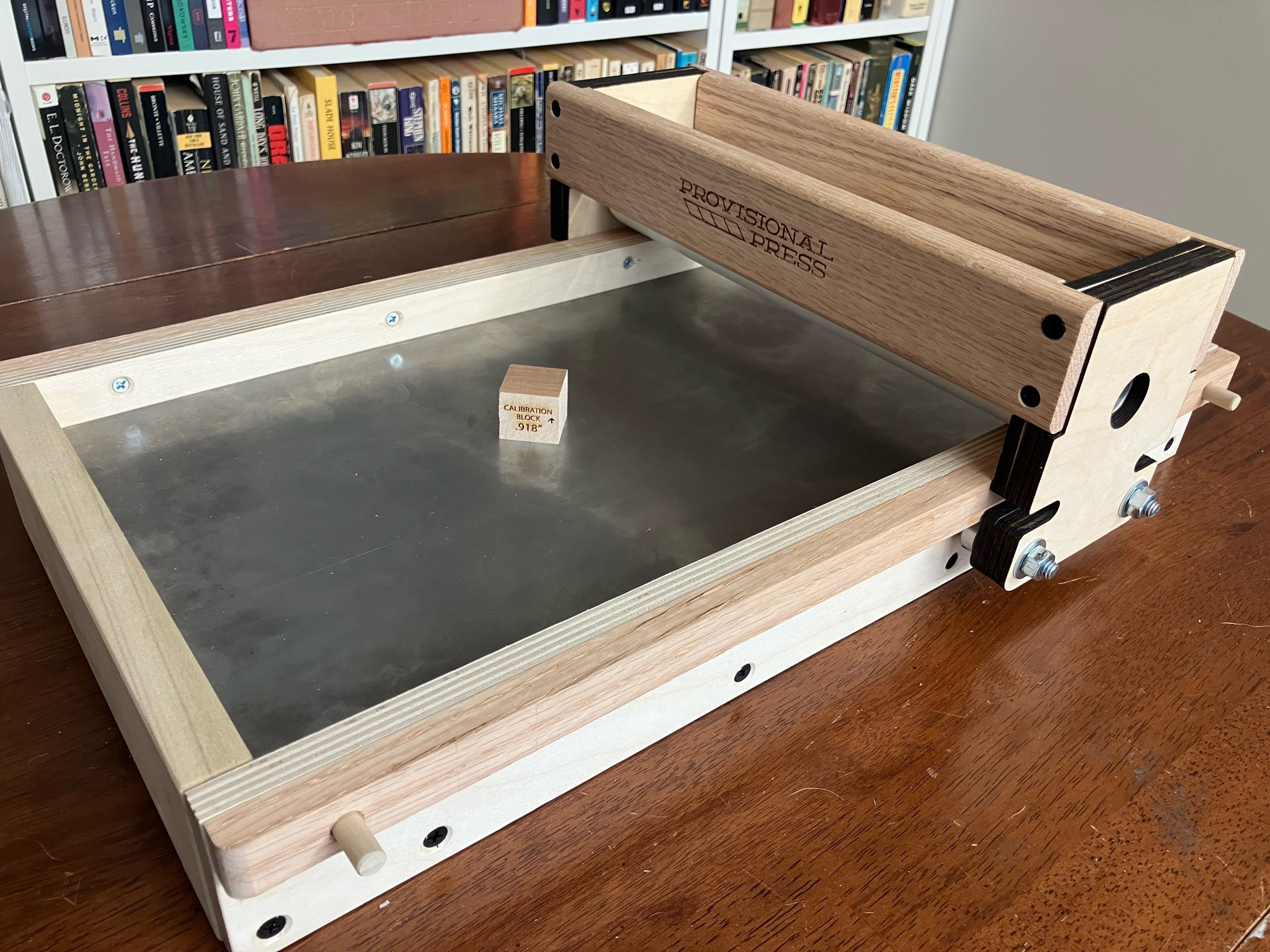 Photo of a Provisional Press tabletop showcard letterpress, made of light-colored wood, PVC pipe, and metal, roughly the size of 3 shoeboxes